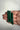 Three polished green malachite crystal points held in a person's hand against a plain off-white background.