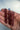 Three pointed berry reddish-brown crystal points held in a person's hand against a plain light background.